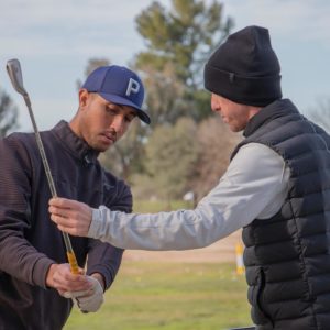 Golf instructor helping student with backswing